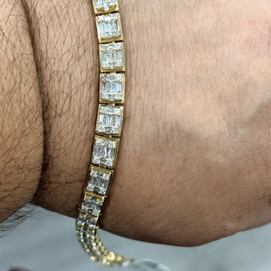 Men's baguette diamond tennis bracelet in 14k yellow gold, worn on the wrist